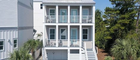 A multi-story building with a garage, a staircase, and a small balcony.