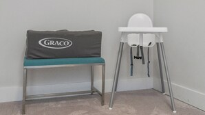 Un espace pour changer les bébés équipé d’un coussin de la marque Graco et d’une chaise haute blanche.