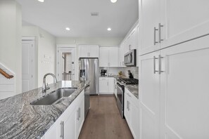 A modern kitchen with white cabinetry, stainless steel appliances, and a granite countertop. - 1/4 mile to Beach~Dogs OK~Pool~Grill~Master Suite (Santa Rosa Beach)