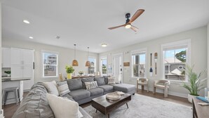 Un salon moderne avec un canapé d’angle gris, une table basse et un ventilateur de plafond.