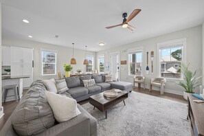 A modern living room with a grey sectional sofa, a coffee table, and a ceiling fan. - 1/4 mile to Beach~Dogs OK~Pool~Grill~Master Suite (Santa Rosa Beach)