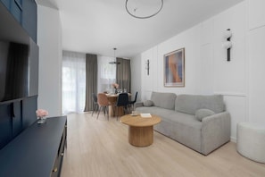 A modern living room with a sofa, a coffee table, and a dining area with chairs and a table. - Family Apartment in the City Centre | 2 Bedrooms | 950 m from the Market Square (Wrocław)