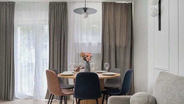Un'area pranzo moderna con un tavolo rotondo, sei sedie e un vaso di fiori.