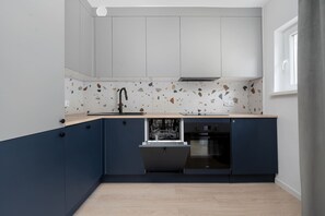 Eine kleine Küche mit Geschirrspüler, Spüle und Fenster.