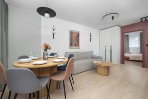 A modern living room with a dining area, a sofa, and a bed. - Family Apartment in the City Centre | 2 Bedrooms | 950 m from the Market Square (Wrocław)