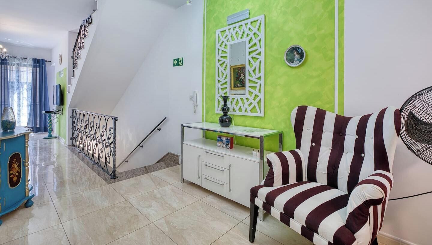 Eine Hotelhalle mit Treppe, einer Couch, einem Schrank und einem Ventilator.