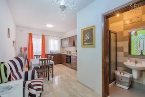 A modern apartment with a dining area, kitchen, and a bathroom with a large mirror and a sink. - Sunny Marsaskala Home w/Roof Terrace & Balconies (Wied il-Għajn)
