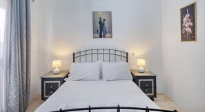 Ein Hotelzimmer mit einem Bett, zwei Nachttischen mit Lampen, einem Schminktisch und einem Bild an der Wand.