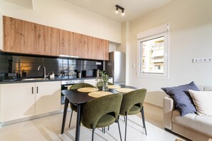 Eine moderne Küche mit Holzschränken, einer schwarzen Arbeitsplatte und einem Essbereich mit grünen Stühlen und einem Tisch.