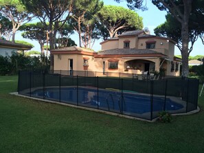 A residential property with a swimming pool, surrounded by a fence, and a house with a tiled roof. - Villa with a pool and a 1,800-meter lot in the Roche Development (Roche)