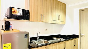 Cocina compacta con refrigerador, microondas y pileta doble.