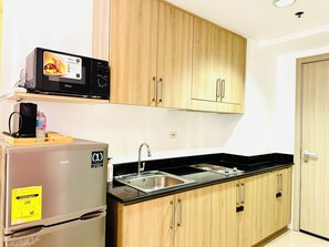 A compact kitchen with a refrigerator, microwave, and a double sink. - Chic 2-bed Family Suite Shore Residences  Pasay City MOA near airport/NAIA/Okada (Pasay City)