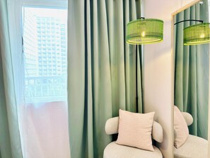 A room with a large mirror, a green floor lamp, and a view of a building through a window with curtains. - Chic 2-bed Family Suite Shore Residences  Pasay City MOA near airport/NAIA/Okada (Pasay City)