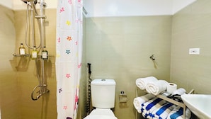 Un baño con ducha, inodoro y un estante con toallas.