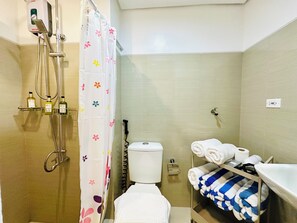 A bathroom with a shower, toilet, and a shelf with towels. - Chic 2-bed Family Suite Shore Residences  Pasay City MOA near airport/NAIA/Okada (Pasay City)