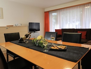 A dining table with a bottle, glasses, and a plate of food in a room with a television and a sofa. - Am Biel 2 Appartement/Fewo 4-Bettwohnung Nr. 2 by Interhome (Saas-Fee)