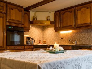 A kitchen with wooden cabinets, a built-in oven, a coffee maker, and a decorative centerpiece on the counter. - Chalet Alpenrösli Appartement/Fewo Alpenrösli 10-Bettwohnung Nr. 1 by Interhome (Saas-Almagell)