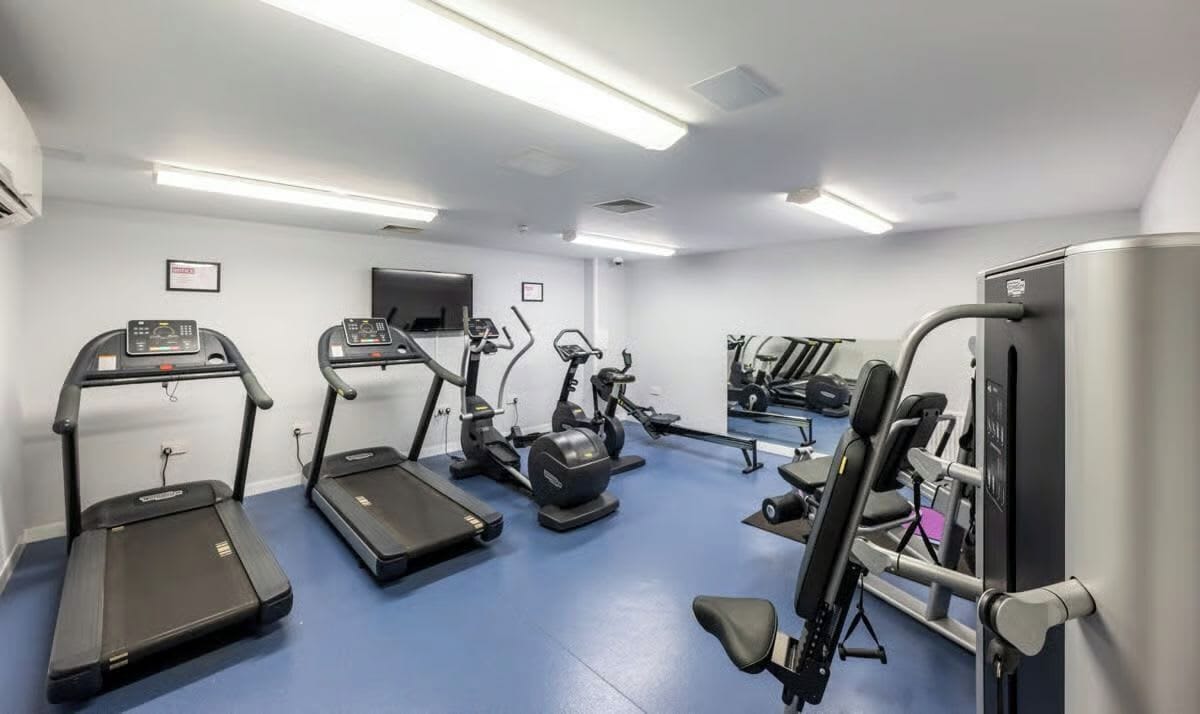 Un gimnasio con cintas de correr, elípticas y equipo de pesas.