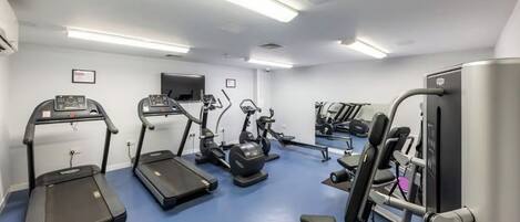 Un gimnasio con cintas de correr, elípticas y equipo de pesas.