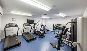 Ein Fitnessraum mit Laufbändern, Crosstrainern und Gewichten.