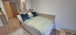 A bedroom with a bed, a nightstand, a dresser, and a door. - Student Only Haddington Place Edinburgh (Edinburgh)