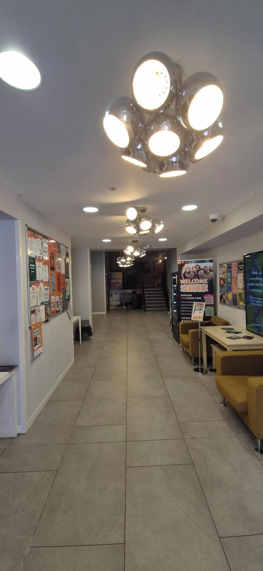A hallway with a reception desk, informational posters, and a staircase leading to another floor.