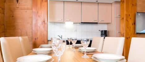 Ein Esszimmer mit Holztisch, gedeckt für sechs Personen, inklusive Teller, Gläser und Besteck.