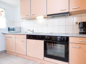 A kitchen with a dishwasher, oven, microwave, and a coffee maker on the counter. - Chalet Alpenrösli Appartement/Fewo Alpenrösli 7-Bettwohnung Nr. 7 by Interhome (Saas-Almagell)