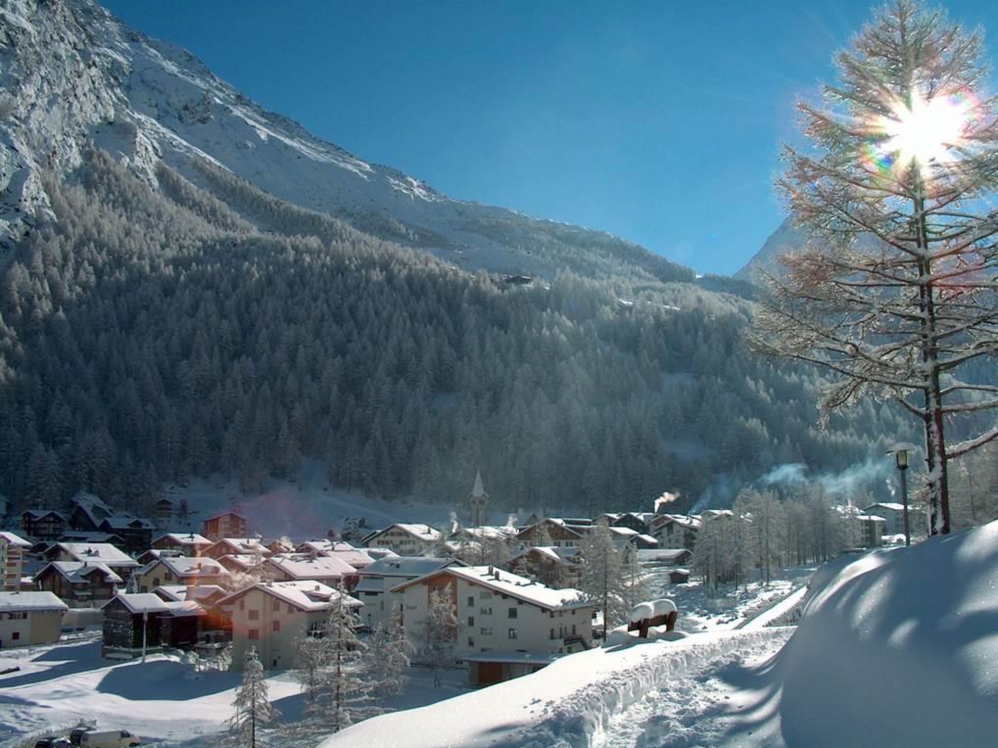 Un pueblo cubierto de nieve con edificios y una montaña al fondo.