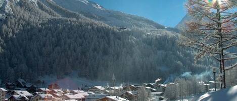 Un pueblo cubierto de nieve con edificios y una montaña al fondo.