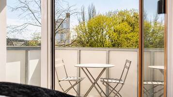 Ein Balkon mit Tisch und Stühlen, Blick auf Bäume und Gebäude.