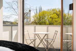 A balcony with a table and chairs, a view of trees and buildings. - The Faces | Comfort Studio | Balcony | 309 (Berlin)