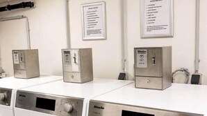 A row of white front-loading washing machines with control panels, mounted on a white countertop.