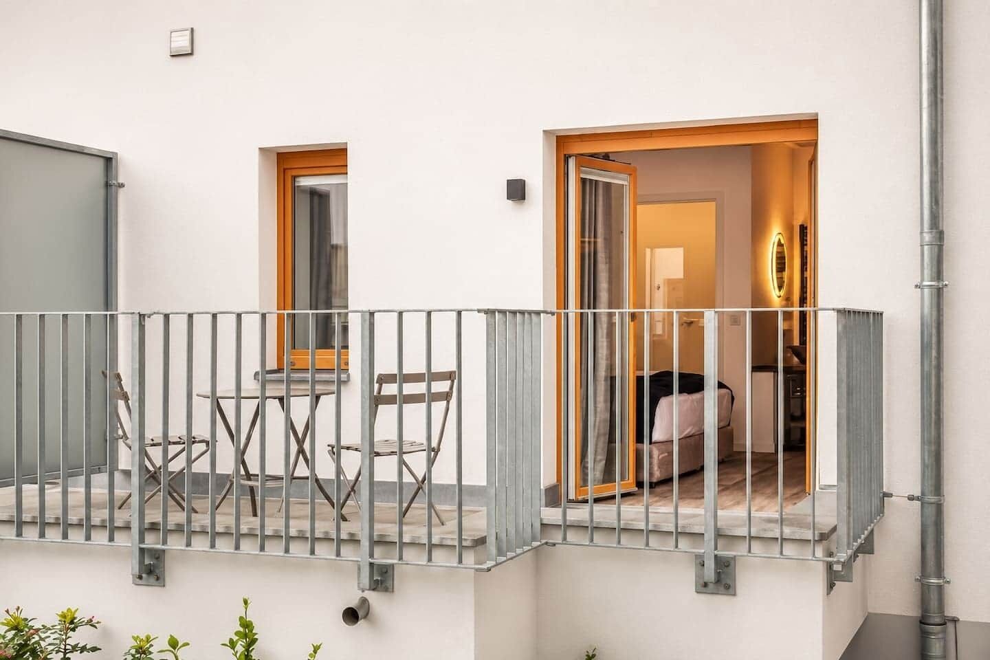 Ein Balkon mit Metallgeländer, einem kleinen Tisch und zwei Stühlen.