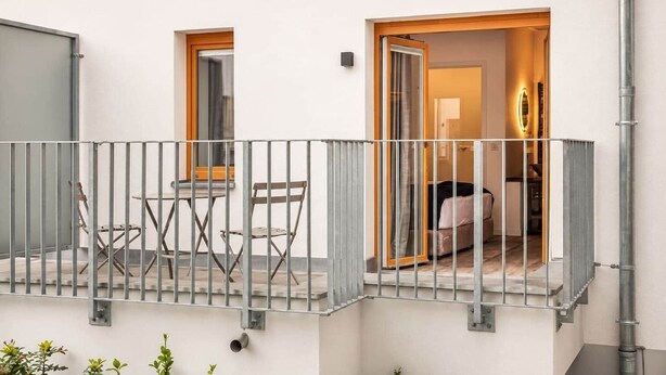A balcony with a metal railing, a small table, and two chairs.