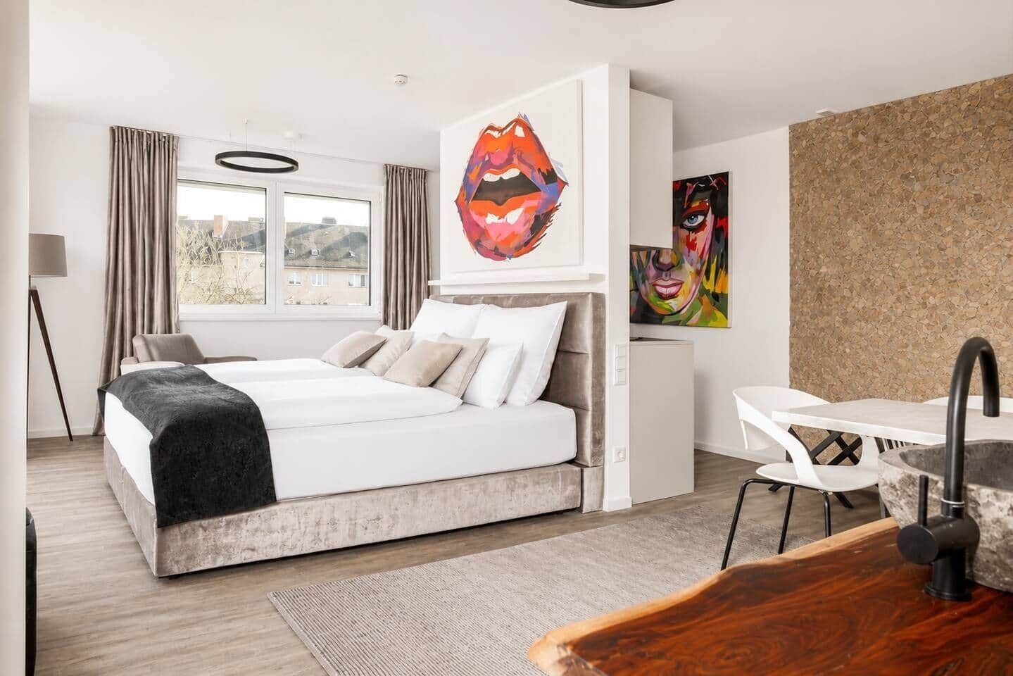 Ein modernes Schlafzimmer mit Bett, Schreibtisch und Bildern an der Wand.