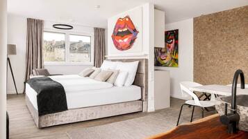 Ein modernes Schlafzimmer mit Bett, Schreibtisch und Bildern an der Wand.