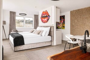 Ein modernes Schlafzimmer mit Bett, Schreibtisch und Bildern an der Wand.
