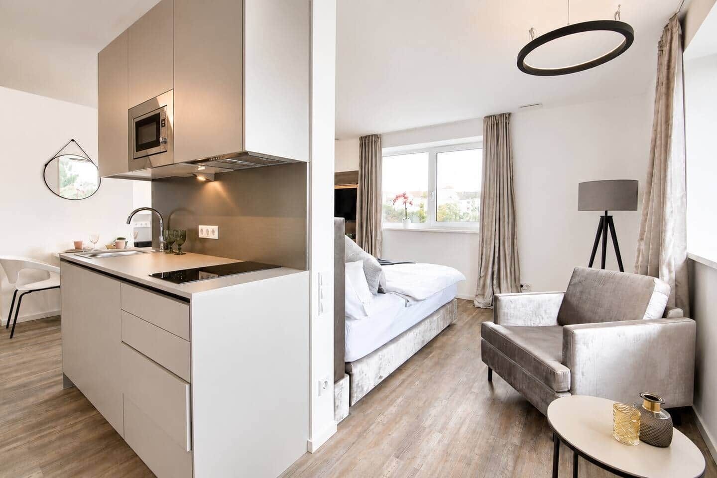 Ein modernes Hotelzimmer mit Küchenzeile, einem Bett, einer Sitzecke und Blick ins Freie.