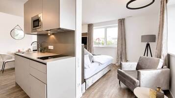 Ein modernes Hotelzimmer mit Küchenzeile, einem Bett, einer Sitzecke und Blick ins Freie.