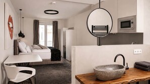A modern kitchen with a stone sink, a microwave, and a hanging light fixture. - The Faces | Premium Studio | Balcony | 201 (Berlin)