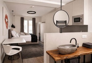 A modern kitchen with a stone sink, a microwave, and a hanging light fixture. - The Faces | Premium Studio | Balcony | 201 (Berlin)