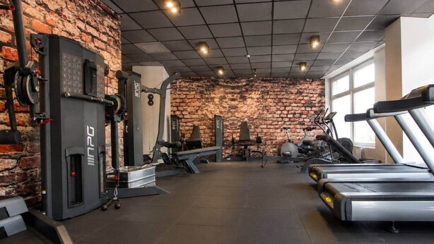 A gym with brick walls, weightlifting equipment, and cardio machines. - The Faces | Premium Studio | Balcony | 201 (Berlin)