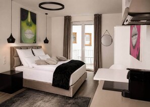 A modern bedroom with a bed, bedside tables, a desk, and artwork on the walls. - The Faces | Premium Studio | Balcony | 201 (Berlin)