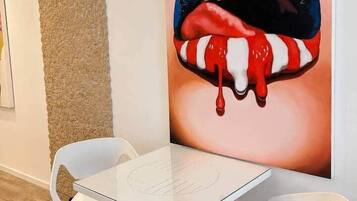 Ein modernes Interieur mit einem weißen Tisch, zwei weißen Stühlen, einer strukturierten Wand und einem großen Gemälde von Lippen mit Sternen.