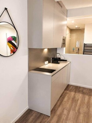 A compact kitchen with a modern design, featuring a built-in sink and a microwave. - The Faces | Premium Studio | Balcony | 203 (Berlin)