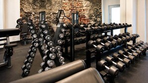 A gym with weightlifting equipment, a bench, and a brick wall backdrop. - The Faces | Premium Studio | Balcony | 203 (Berlin)