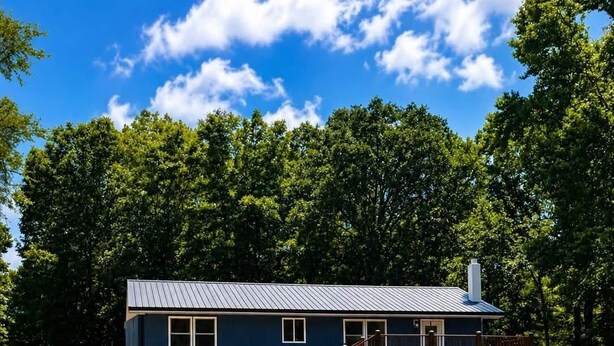 Een gelijkvloers huis met een grindpad dat leidt naar een houten terras.
