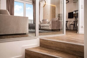 A modern living room with a sofa, armchairs, and a dining area with chairs and a table. - The Faces | Suite | Balcony | 001 (Berlin)