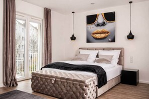 A bedroom with a bed, bedside tables, a large window, and a view of buildings outside. - The Faces | Suite | Balcony | 001 (Berlin)